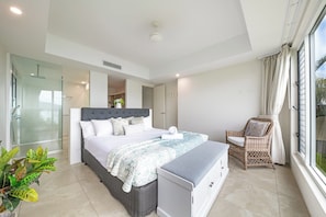 A modern bedroom with a large bed, a bedside table, a chair, and a view of the outdoors.