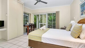 Ein Schlafzimmer mit Bett, Deckenventilator, Fernseher, Schreibtisch und Stuhl.