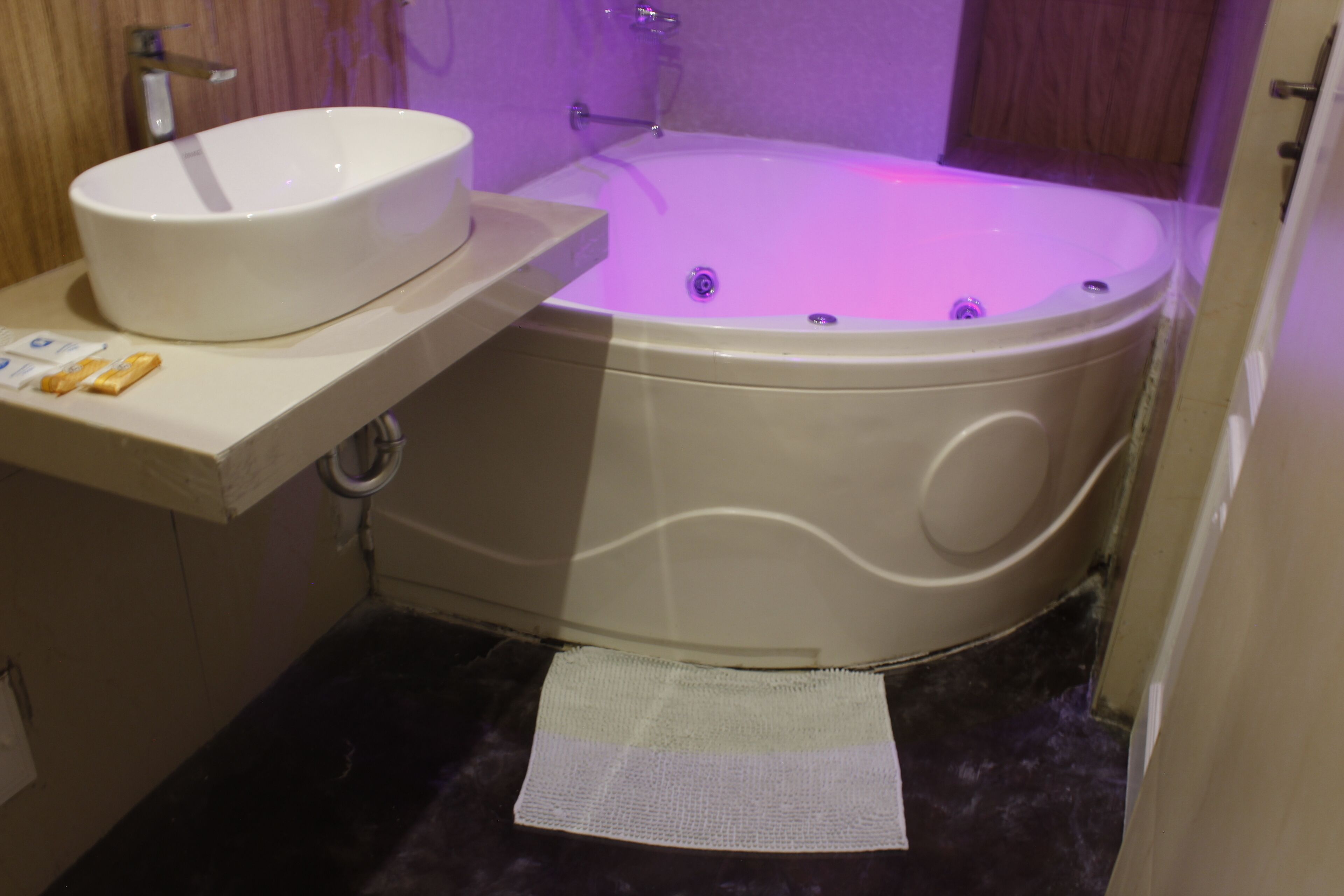 A bathroom with a white bathtub, a sink, and a small towel on the floor.