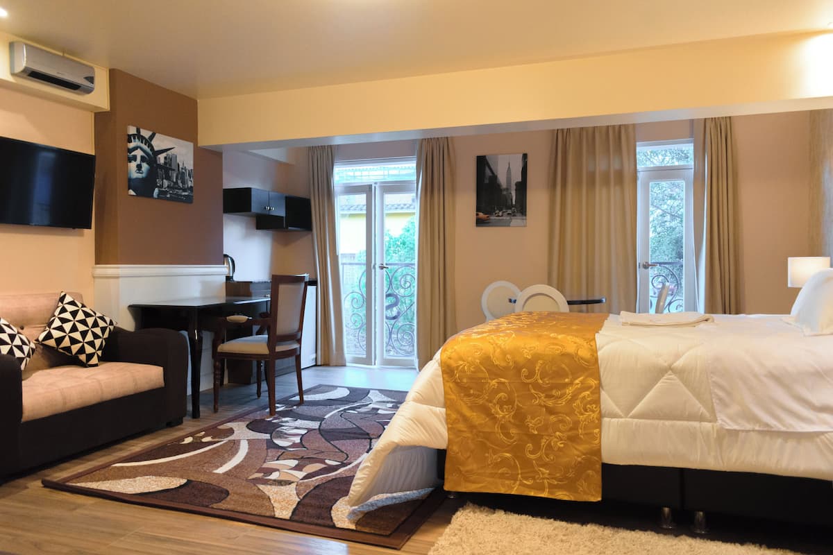Ein Hotelzimmer mit Bett, Sofa, Schreibtisch und Fernseher.
