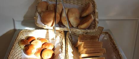 Two wicker baskets on a table containing various breads.