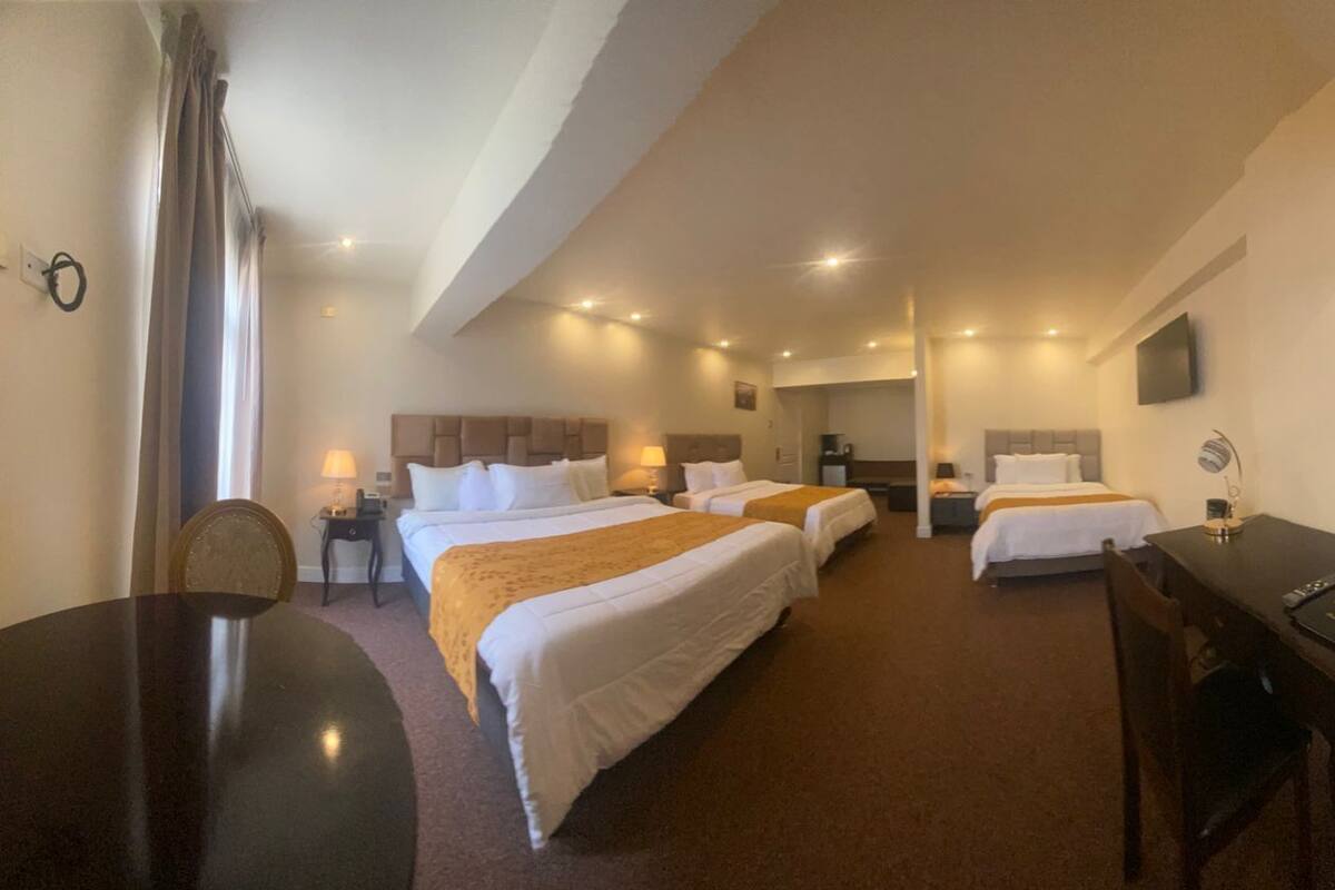 Ein Hotelzimmer mit zwei Betten, einem Schreibtisch, einem Stuhl, einem Fernseher und einer Lampe.