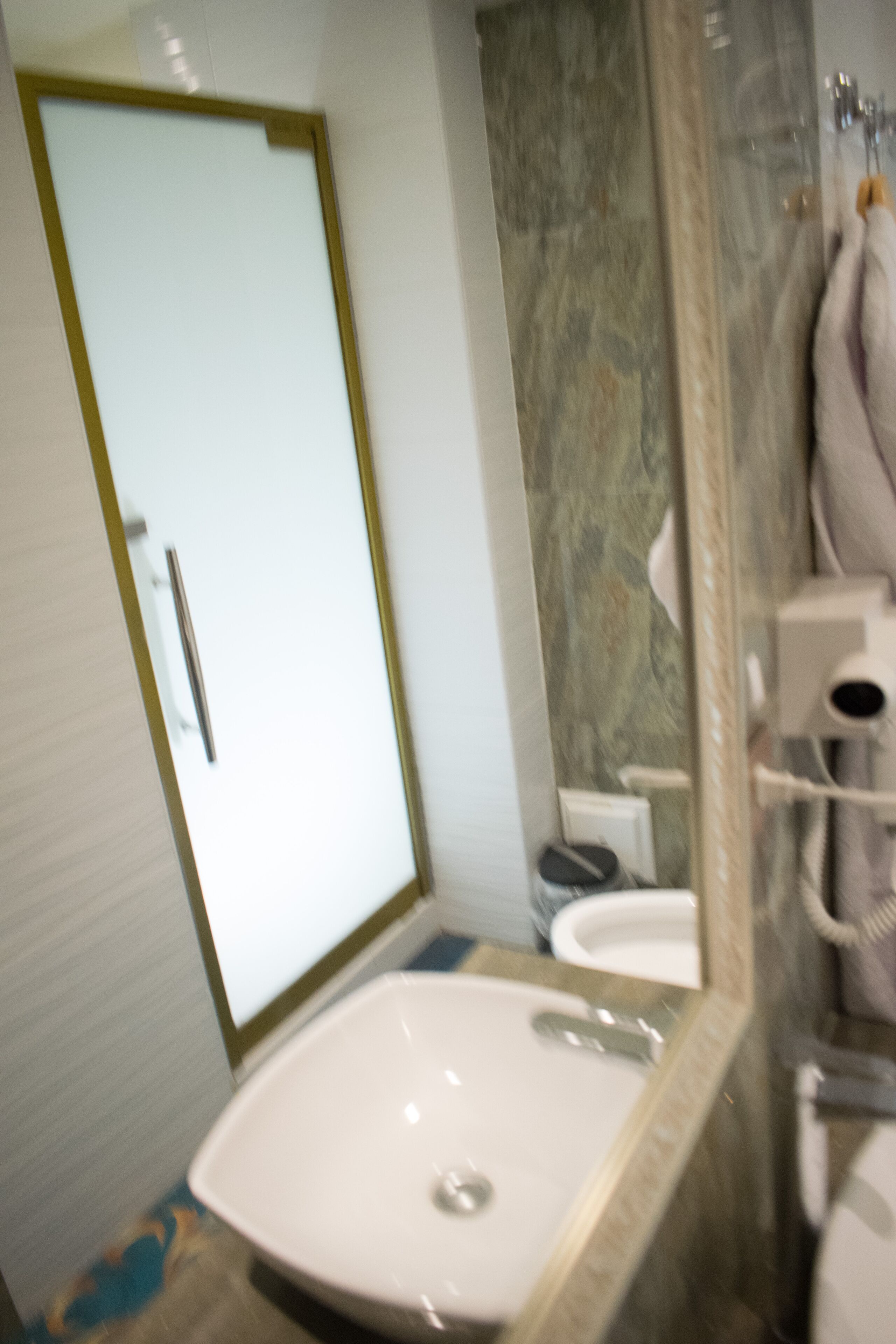 Un baño con lavamanos blanco, un espejo y una zona de ducha.