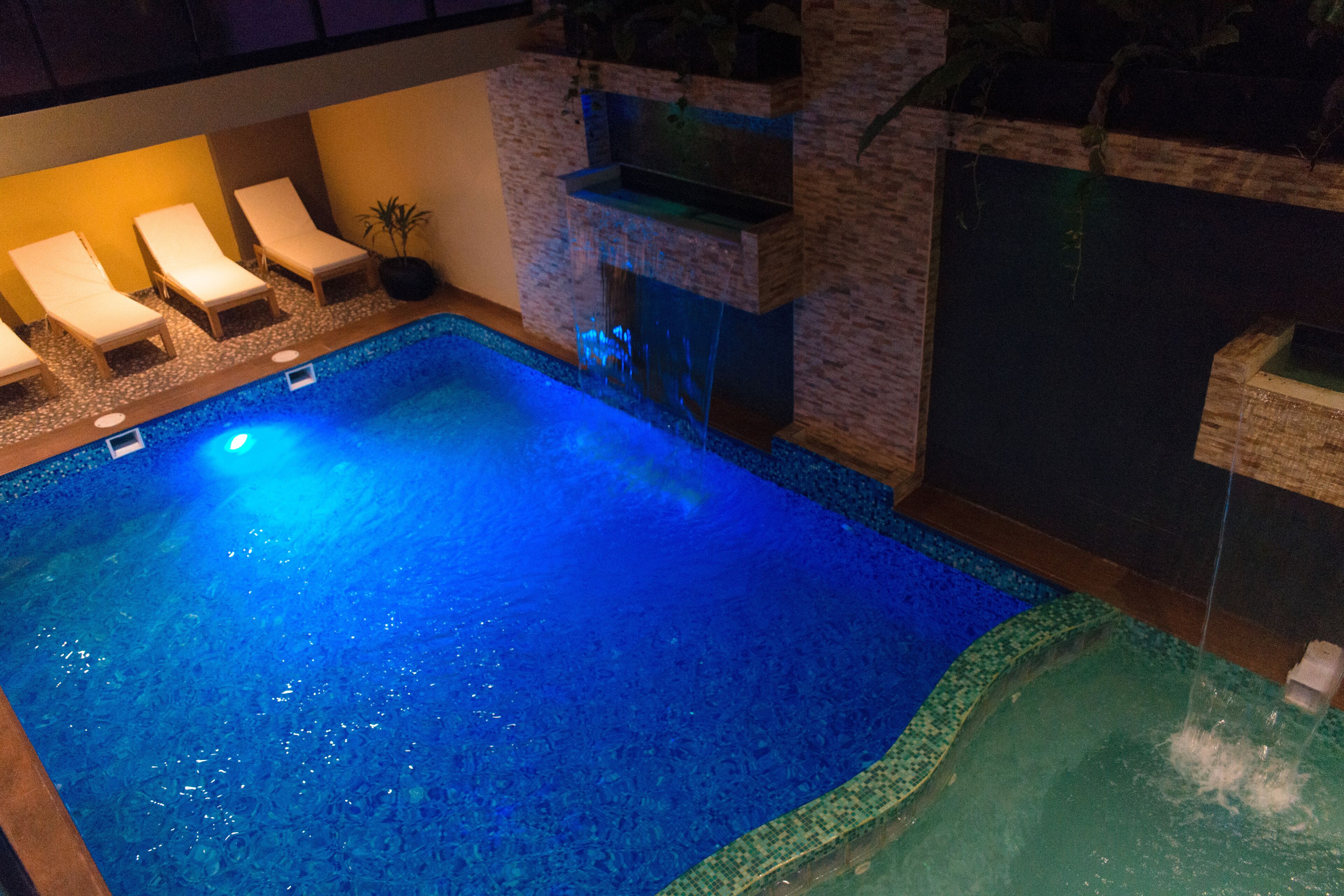 A swimming pool with lounge chairs and a waterfall feature.
