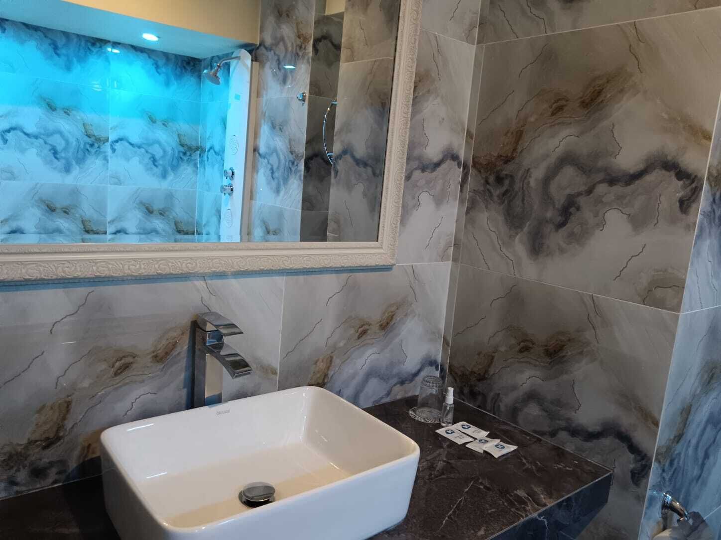 Ein Badezimmer mit Marmorwaschtisch, einer Duschkabine aus Glas und einem großen Spiegel.