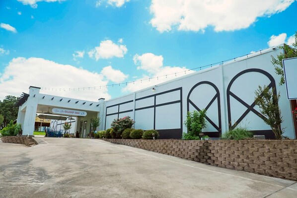 A hotel entrance with a modern design, featuring a large archway and a brick wall. - Lone Star Glamp Inn (Round Top)