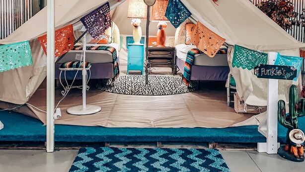 A tent-like room with a bed, a chair, and a lamp. - Lone Star Glamp Inn (Round Top)