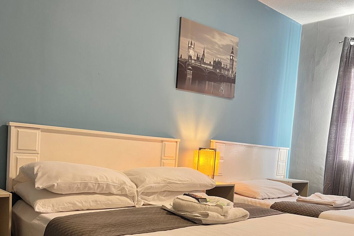 A hotel room with a large bed, a bedside table, a lamp, and a painting of a cityscape.