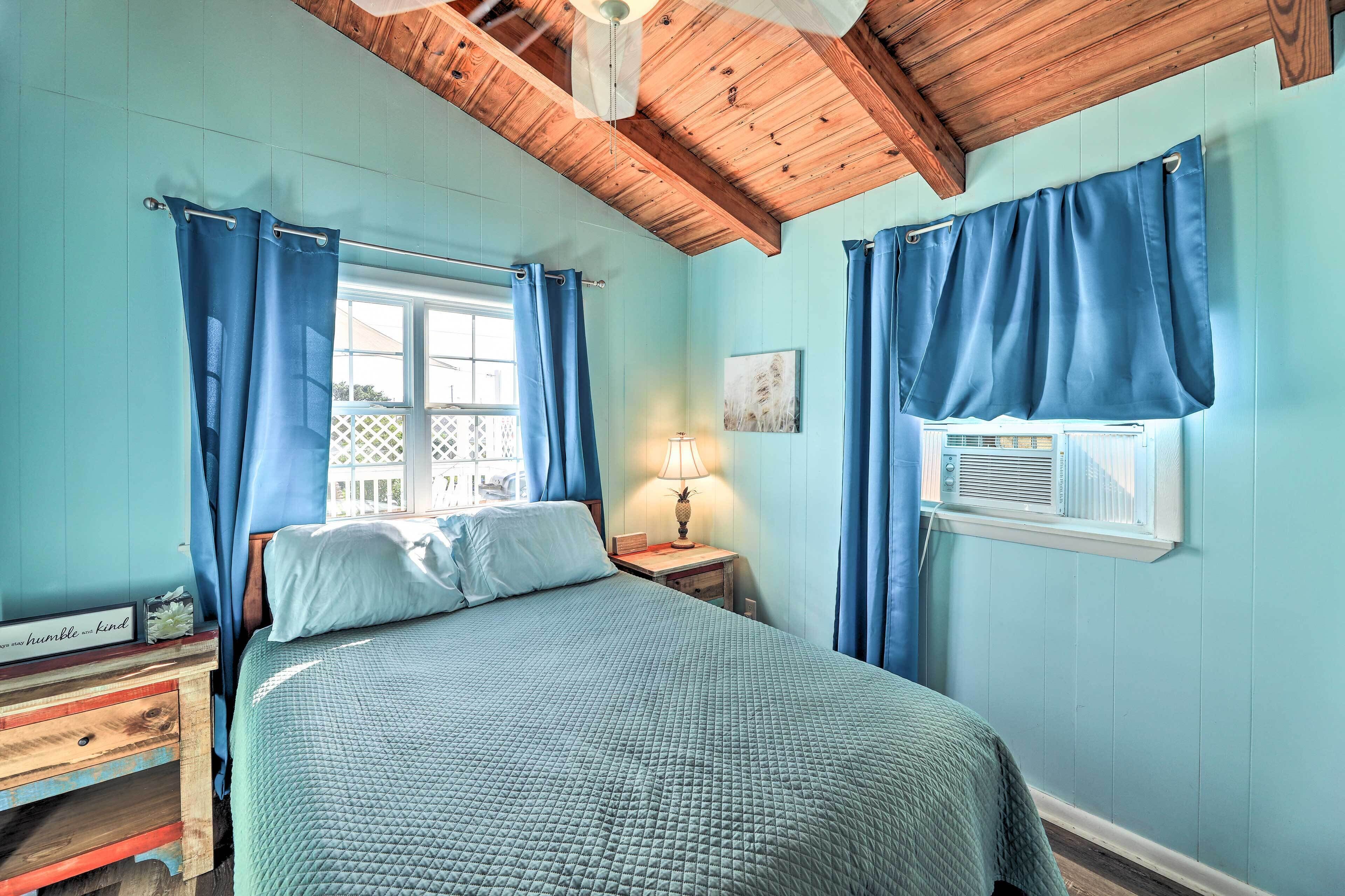 A bedroom with a bed, a nightstand, a lamp, and a window with curtains.