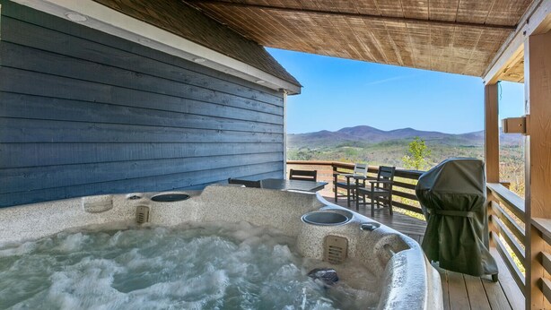 Ett område med ett bubbelbad och en träaltan med utsikt över bergen.