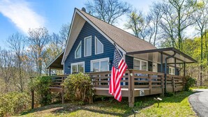 Ett blått hus med en veranda, en amerikansk flagga och en skylt med siffran 76.
