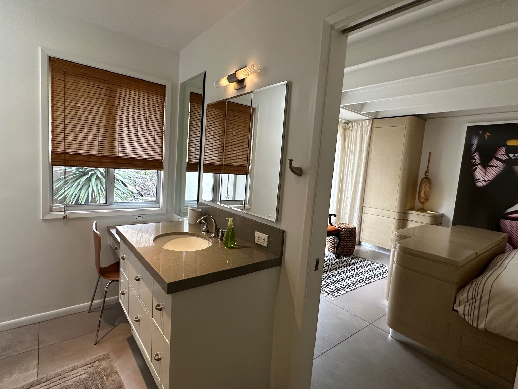 Un bagno moderno con doppio lavandino, uno specchio grande e una finestra con persiane.