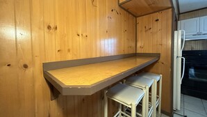 Une cuisine avec des murs en bois, un plan de travail et un réfrigérateur.