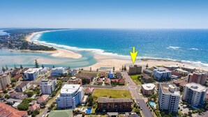 A coastal urban area with a beach, residential buildings, and a road leading to the beach.
