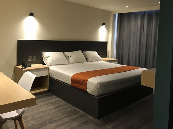 A modern hotel room with a large bed, bedside tables, a desk, and a chair. - Hotel Conde Alameda - CDMX (Mexico City)