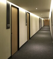 Un pasillo con puertas numeradas 101 y 102, pisos alfombrados e iluminación empotrada.