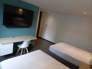 Une chambre d’hôtel avec un lit, un bureau, une chaise et un téléviseur.