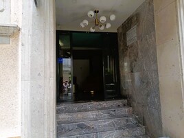 Unos escalones de mármol conducen a un espacio interior oscuro con una lámpara en el techo.