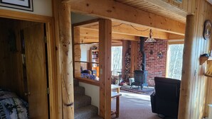 Un intérieur chaleureux en bois, avec une cheminée, un escalier et une bibliothèque.
