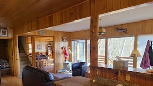 L’intérieur chaleureux d’un chalet comprend un coin cuisine, des murs en bois, un espace repas et un escalier menant à une mezzanine.