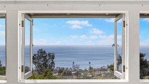 A window with an open view of the ocean and a coastal town. - Charming Cottage with Beautiful Ocean Views (Laguna Beach)