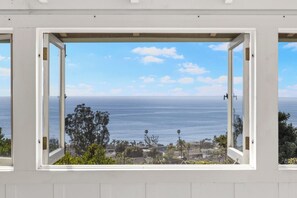 A window with an open view of the ocean and a coastal town.