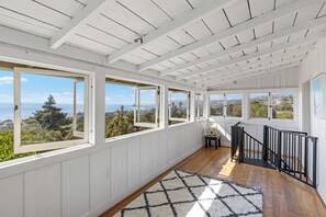 A spacious room with large windows, wooden flooring, and a black railing. - Charming Cottage with Beautiful Ocean Views (Laguna Beach)