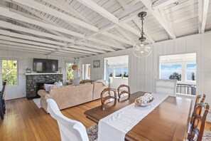 A spacious living room with a stone fireplace, a large TV, and a dining area with a wooden table and chairs.