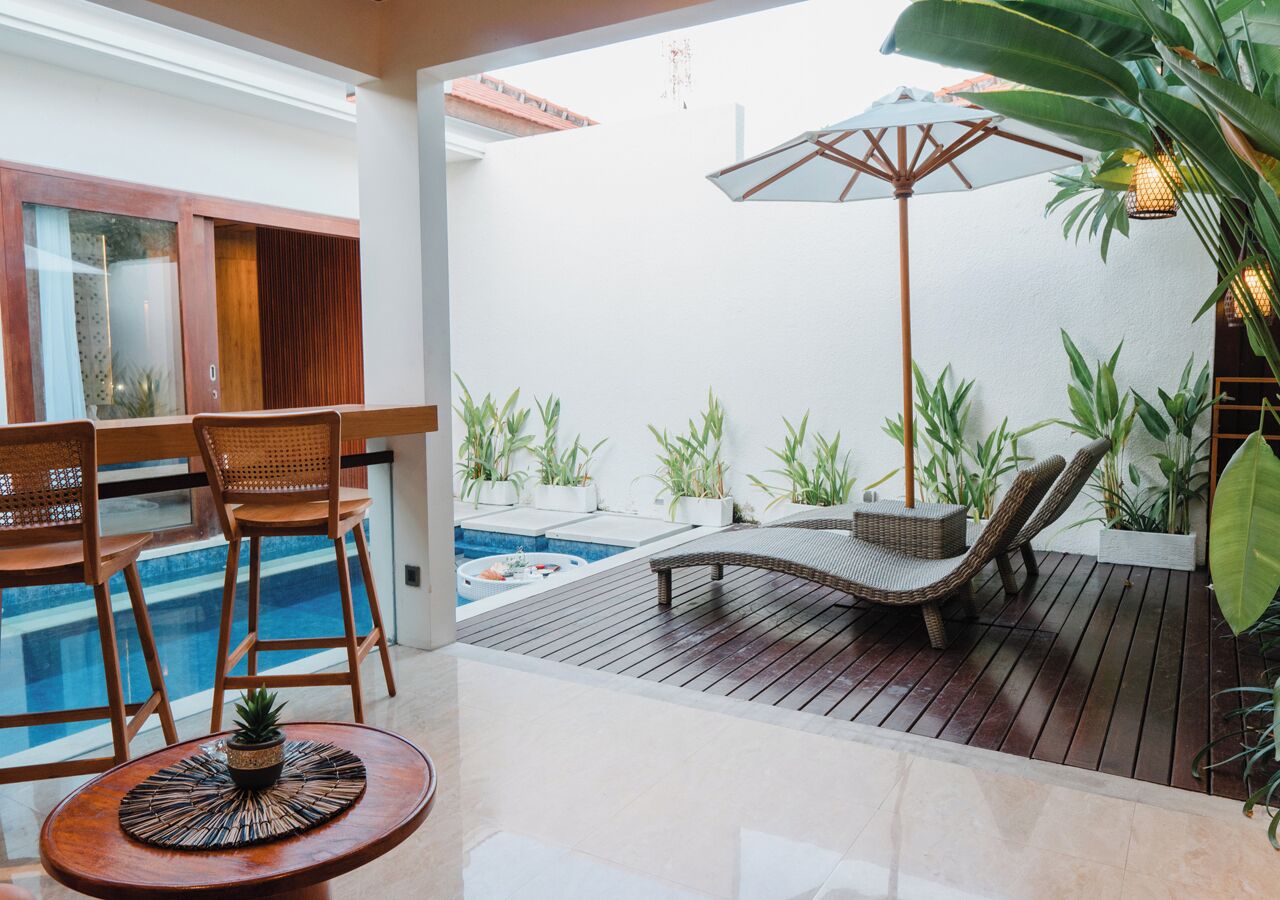 A poolside area with wooden deck, lounge chairs, and potted plants.