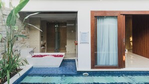 A modern outdoor pool area with a jacuzzi, stone walls, and a wooden door. -  The Mavila Sanur (Denpasar)