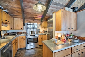 Una cocina moderna con armarios de madera, electrodomésticos de acero inoxidable y una isla central.
