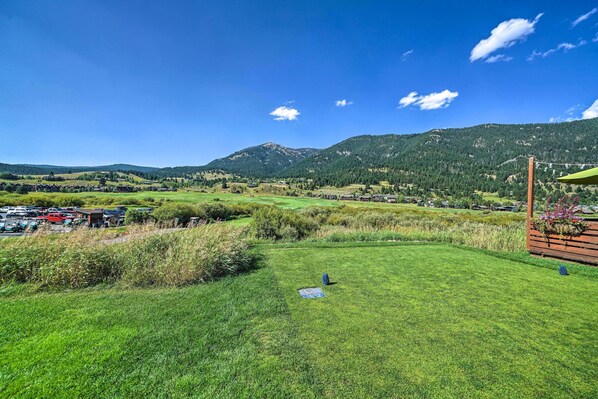 Camp de gespa amb una construcció de fusta i vista a un paisatge montanyós.