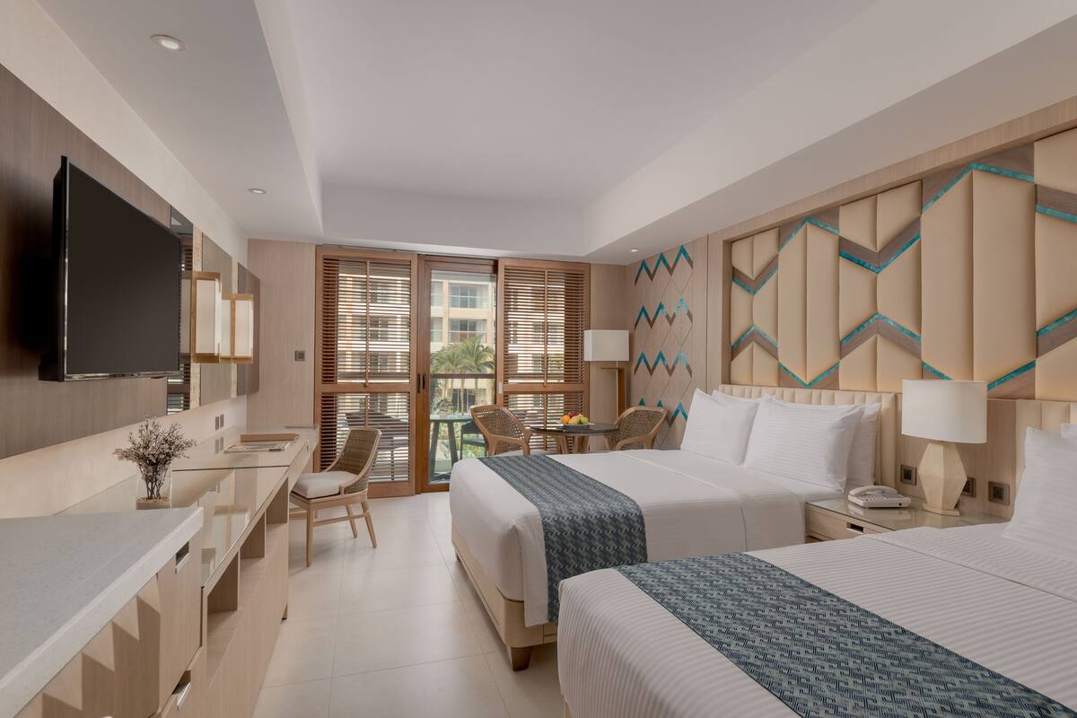 Ein modernes Hotelzimmer mit einem großen Bett, einem Schreibtisch, einem Stuhl und einem Balkon mit Blick.