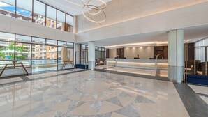 A spacious lobby with a reception desk, large windows, and a decorative ceiling light. - Henann Tawala Resort (Panglao)