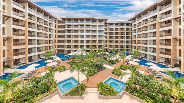 A multi-story hotel with a central pool area surrounded by lush greenery and multiple balconies. - Henann Tawala Resort (Panglao)