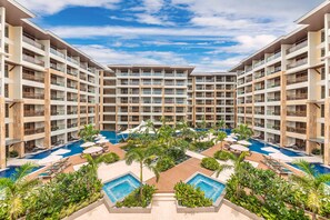 A multi-story hotel with a central pool area surrounded by lush greenery and multiple balconies. - Henann Tawala Resort (Panglao)