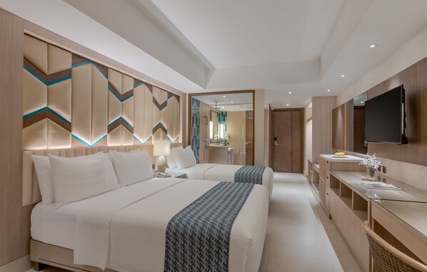 A modern hotel room with two beds, a glass desk, and a flat-screen TV. - Henann Tawala Resort (Panglao)