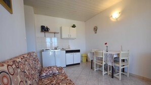 A compact living space with a kitchenette, a dining area, and a sofa. - Apartment Marinela 1 (Njivice)