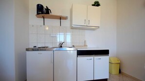 A compact kitchen with a built-in dishwasher, a sink, and a small trash bin. - Apartment Marinela 1 (Njivice)