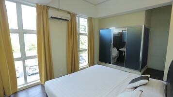Habitación de hotel con cama, armario, baño y vistas al exterior.