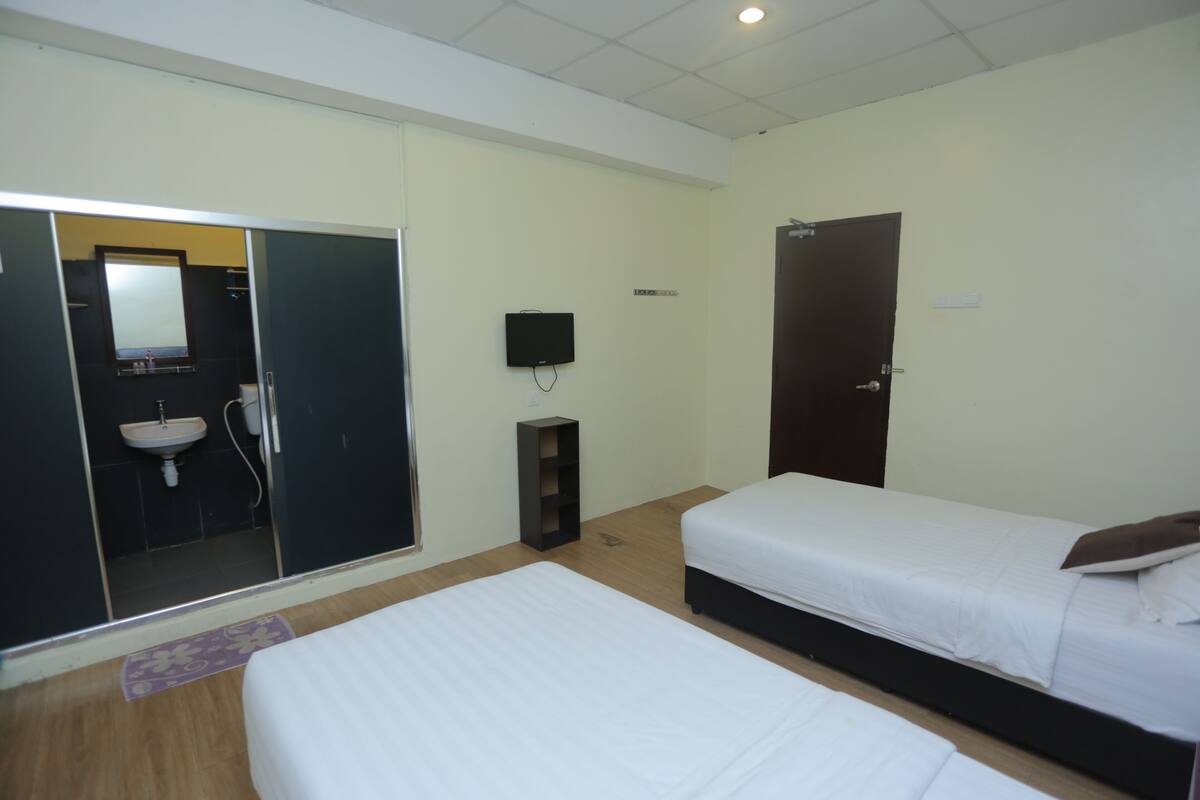 Een hotelkamer met twee bedden, een badkamer met een wastafel, een spiegel en een televisie.