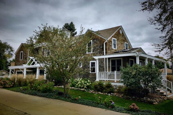 A two-story house with a porch, surrounded by a well-maintained garden. - Hot tub relaxing retreat. Large group gatherings! Business travel. (Kenosha)
