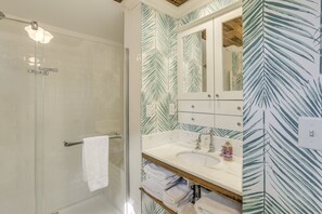 A bathroom with a glass shower enclosure, a white sink with a mirror above it, and a towel rack. - Hot tub relaxing retreat. Large group gatherings! Business travel. (Kenosha)