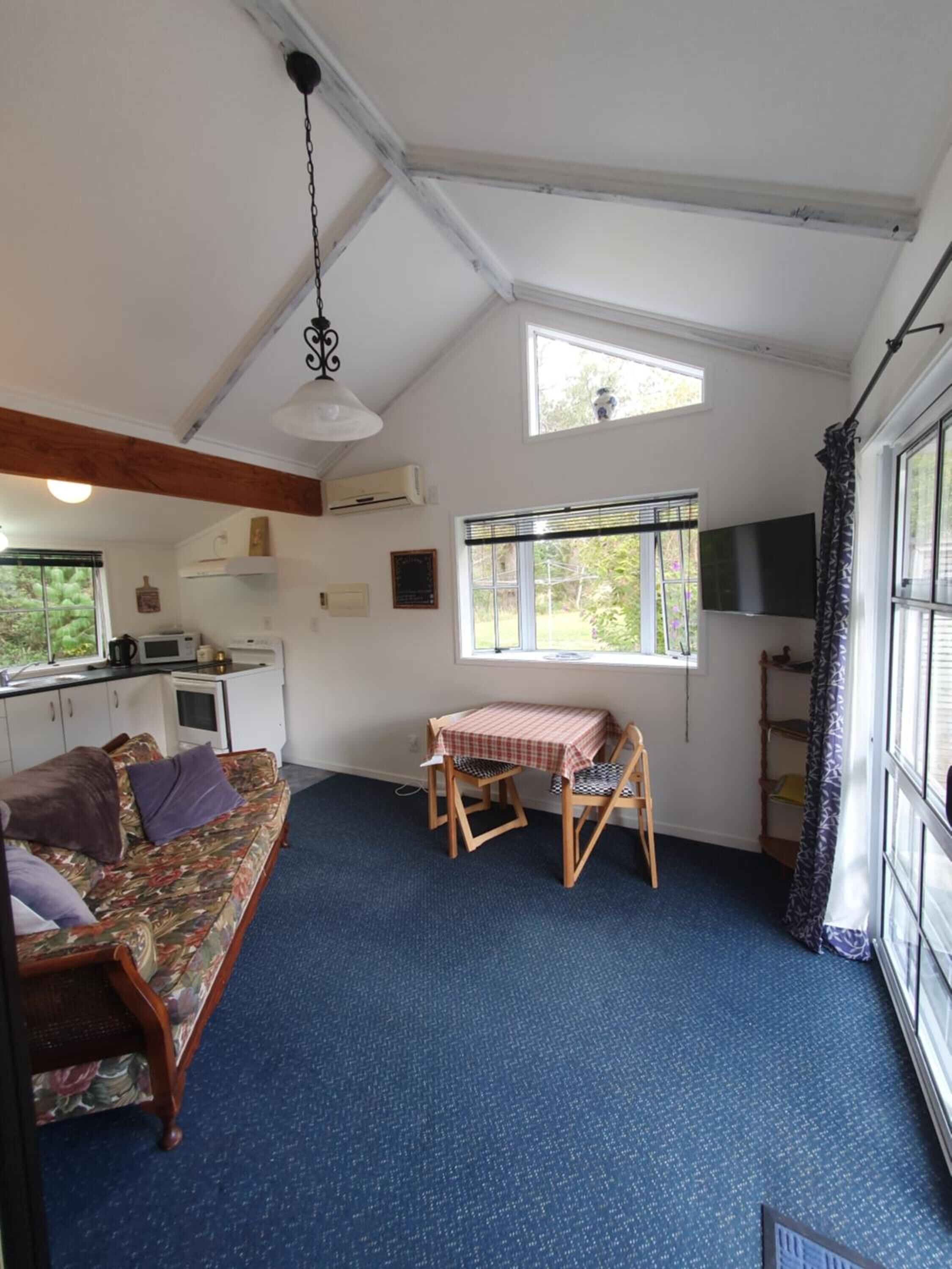 A compact room with a sofa, a small table, a TV, and a window with blinds.