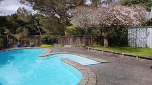 A swimming pool with a wooden deck and a wooden fence in the background. - Poripori Homestead (Lower Kaimai)