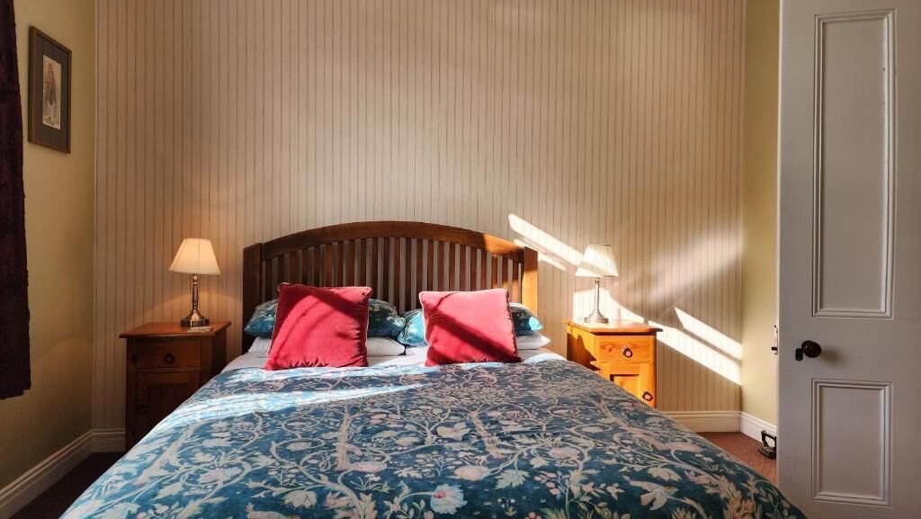 Un dormitorio con una cama, dos mesitas de noche y una puerta.