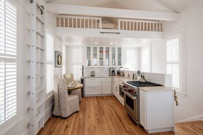 Eine Küche mit weißen Schränken, einem Herd und einem Essbereich mit Stuhl und Tisch.