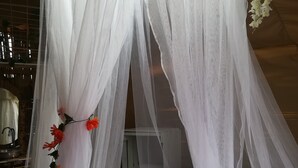 A bed with a white canopy and a basket of towels. - Qji Bio Hotel Glamping (Villavieja)