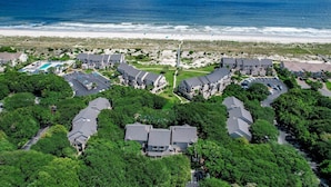 Vista aerea di una zona residenziale costiera con case, una spiaggia e un cielo sereno.