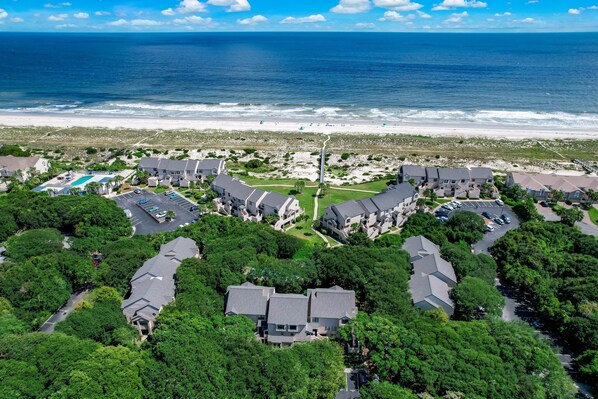 An aerial view of a coastal residential area with houses, a beach, and a clear sky.